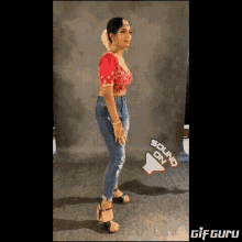 a woman wearing a red top and blue jeans is standing in front of a sign that says sound on .
