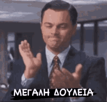 a man in a suit and tie is clapping his hands in front of a sign that says megaah doyleia
