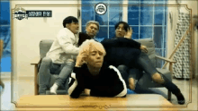 a group of young men are sitting on a couch and playing with each other .