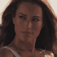 a close up of a woman 's face with a white tank top on