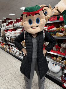 a woman in a black jacket and overalls stands in front of a shelf that says ho ho