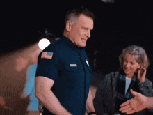 a man in a police uniform with an american flag on his shoulder shakes hands with another man