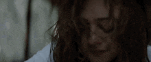 a woman with curly hair is crying with her eyes closed and her hair blowing in the wind .