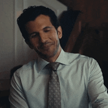 a man wearing a striped shirt and tie is smiling with his eyes closed