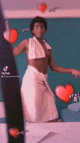 a man in a white towel is dancing in front of a wall with hearts and the word tiktok