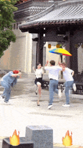 a man holding a rainbow colored umbrella is being photographed by two other men