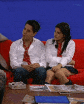 a man and a woman sitting on a red couch