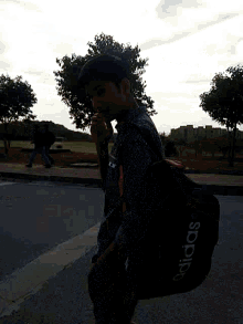 a man carrying a black adidas duffel bag