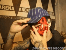 a man with a mask on his face is wearing a hat in front of a sign that says arena
