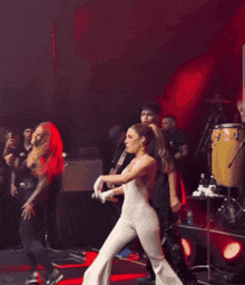 a woman in a white outfit is dancing on stage