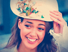 a woman wearing a hat with flowers on it is smiling