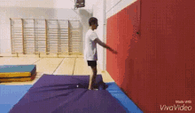 a boy is jumping on a trampoline in a gym .
