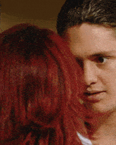 a man with red hair looks at a woman