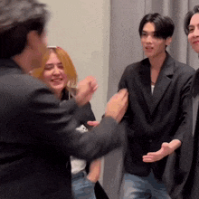 a group of people are standing next to each other in a room and talking to each other .