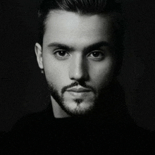 a close up of a man 's face with a beard in a black and white photo