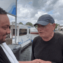 two men are shaking hands in front of a boat that says audi