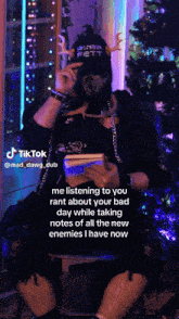 a man sitting in front of a christmas tree with a tiktok written on the bottom right