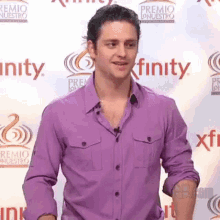 a man in a purple shirt stands in front of a wall that says finity