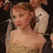 a woman in a green dress is sitting in a crowd .