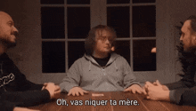 a group of men are sitting around a table and one of them says " oh vas niquer ta mere "