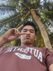 a man wearing a t-shirt with the word tua on it is giving a peace sign