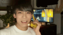 a young man is holding a banana in front of a tv screen with the letter s on it