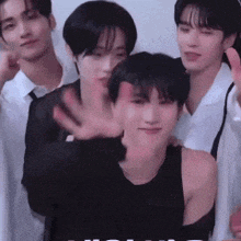 a group of young men are posing for a picture and one of them is waving at the camera .