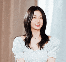 a woman wearing a white top with puffed sleeves smiles for the camera