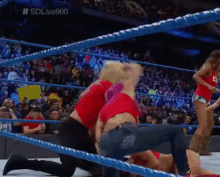 a woman in a red shirt is kneeling down in a wrestling ring with # sdlive900 on the bottom
