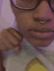 a close up of a person 's face with glasses and a nose ring .