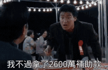a man in a suit and tie is standing in front of a table with chinese characters on it .