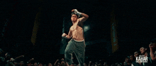 a man without a shirt is standing in front of a kahar sign