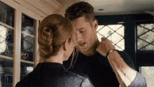 a man and a woman are standing next to each other in a kitchen and kissing .