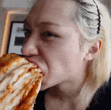a woman is eating a slice of pizza with her mouth open