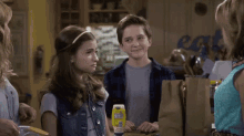 a boy and a girl are standing next to each other in a kitchen with a sign that says eat in the background .