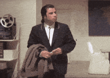 a man in a suit and tie is standing in a room holding his jacket