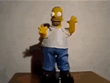 a statue of homer simpson is standing on a wooden table
