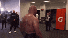 a man without a shirt is standing in front of a gatorade banner