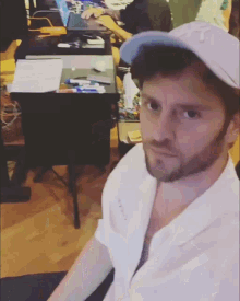 a man wearing a white shirt and a ny hat sits in front of a desk