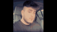 a man with a beard is sitting in a car and looking at the camera
