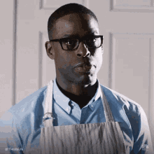 a man wearing an apron and glasses is looking at the camera .