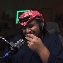 a man wearing headphones and a red and white head scarf covering his face in front of a microphone