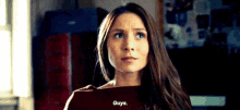 a woman with long brown hair is standing in a room and talking to someone .