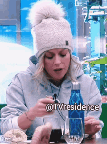 a woman sitting at a table with a bottle of water and a glass of wine with the hashtag @tvresidence