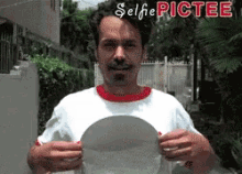 a man in a white shirt is holding a plate with the words selfie pictee written on it