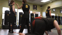 a group of people are practicing martial arts in a gym wearing black uniforms with a dragon on the back