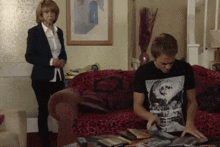 a man wearing a black t-shirt with a picture of a woman on it is sitting on a couch
