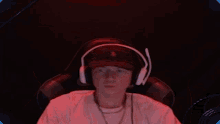 a young man wearing headphones and a hat is sitting in a chair in a dark room .