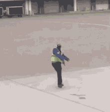 a man wearing a yellow vest and a blue shirt is holding a pink stick