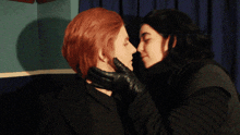 a man with red hair kisses a woman with black hair